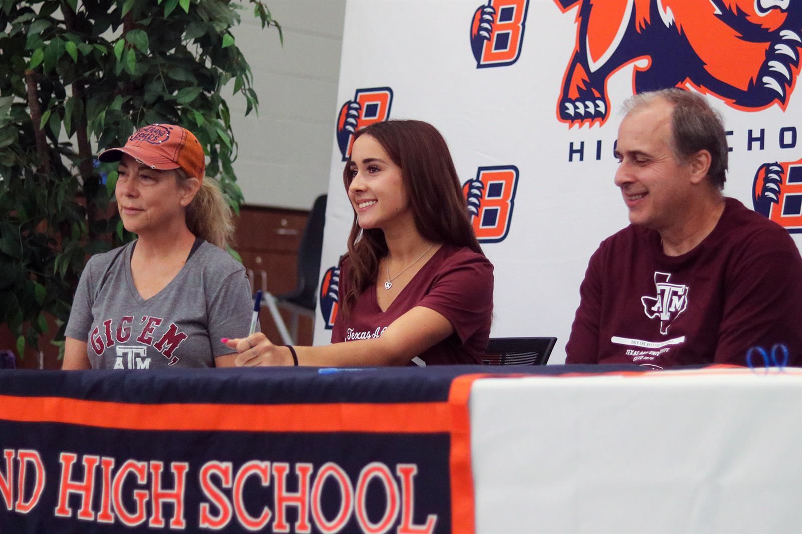 Bridgeland senior Cassidy Graham, center, poses with her parents after signing a letter of intent to run cross country.